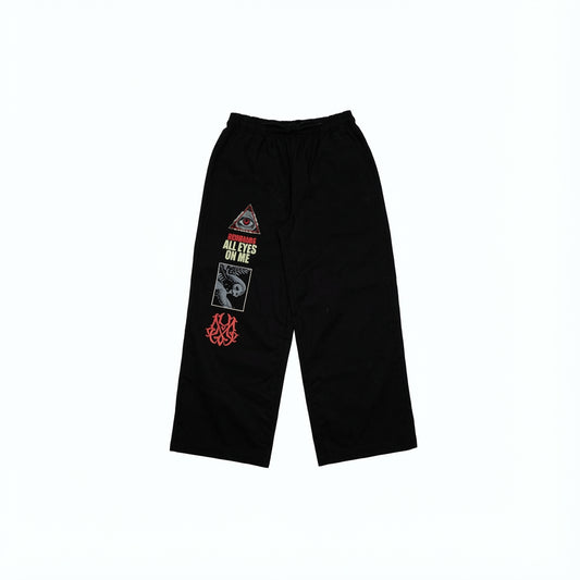 Black twill pants with eye, owl, and text graphics.